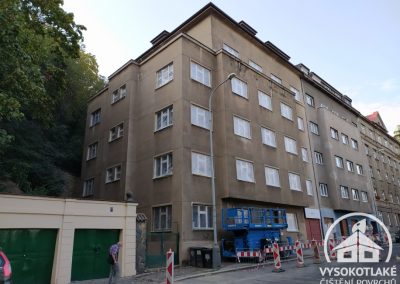 Znečištěná fasáda staršího bytového domu v Praze 5