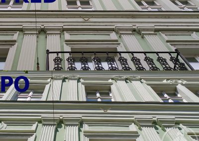 Detail stavu historické fasády domu v Praze v ulici Ječná před čištěním a po